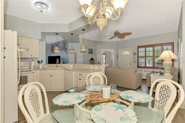 dining space featuring ceiling fan with notable chandelier and wood finished floors