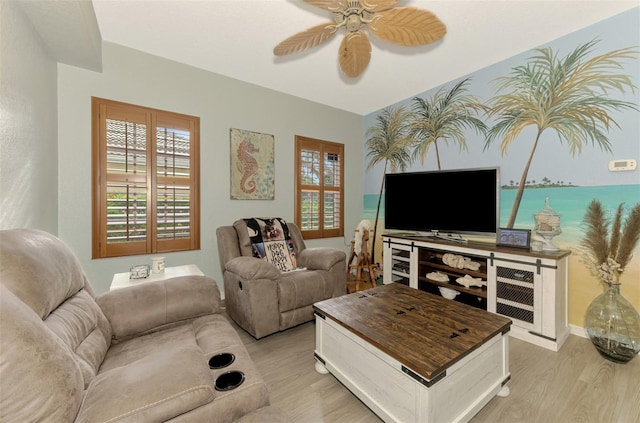 living area featuring a wealth of natural light, baseboards, ceiling fan, and light wood finished floors