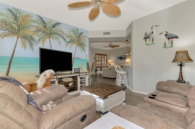 living area with a ceiling fan, visible vents, baseboards, and wood finished floors