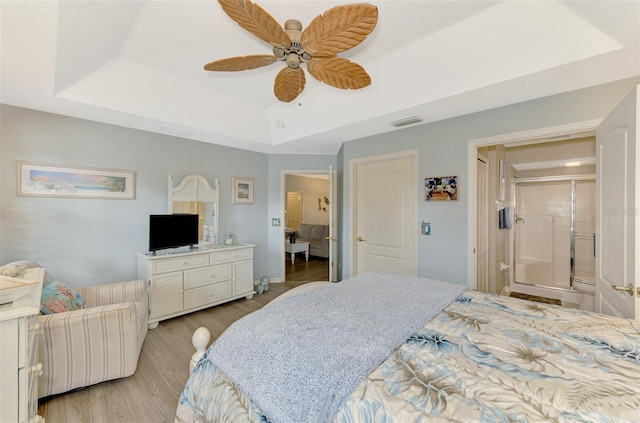 bedroom with light wood-type flooring, ceiling fan, visible vents, and a raised ceiling