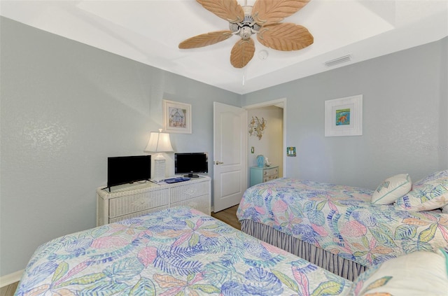 bedroom featuring a ceiling fan, visible vents, and wood finished floors