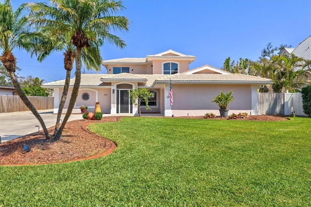 mediterranean / spanish home with a front yard, fence, driveway, and stucco siding