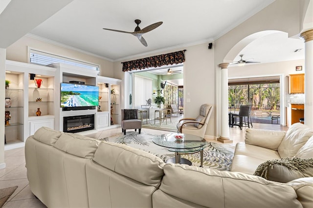 living room featuring crown molding, a glass covered fireplace, light tile patterned flooring, and ceiling fan