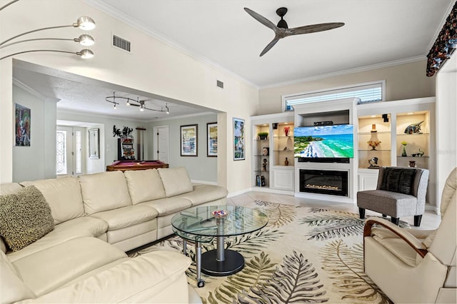 living room featuring tile patterned flooring, visible vents, a wealth of natural light, a glass covered fireplace, and crown molding