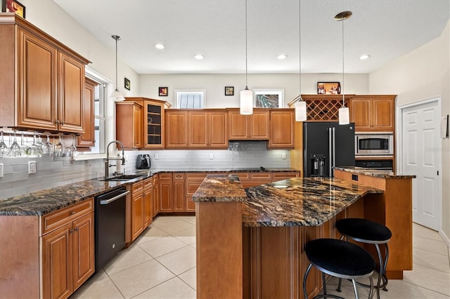 kitchen featuring dishwasher, a kitchen island, stainless steel microwave, high end black fridge, and a sink