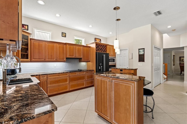 kitchen featuring brown cabinets, a kitchen island, black appliances, and light tile patterned flooring