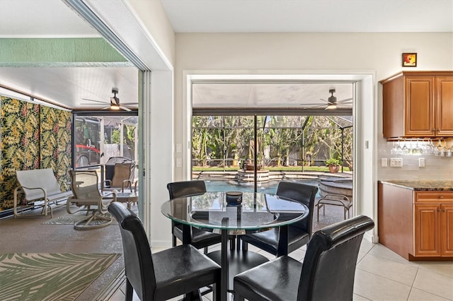 dining room featuring ceiling fan, light tile patterned flooring, and a sunroom