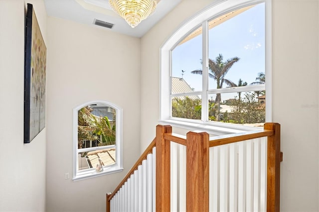 hallway with a chandelier, visible vents, and an upstairs landing