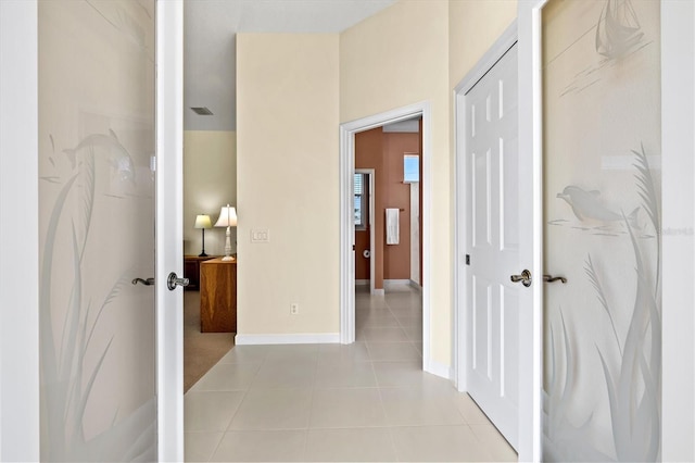 hall with baseboards and light tile patterned floors