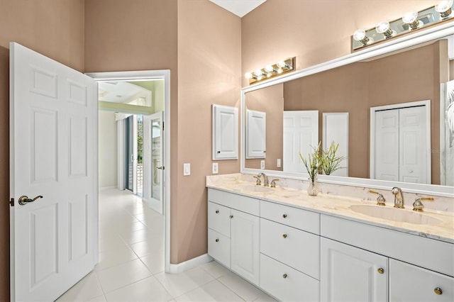 bathroom with tile patterned flooring, a sink, baseboards, and double vanity