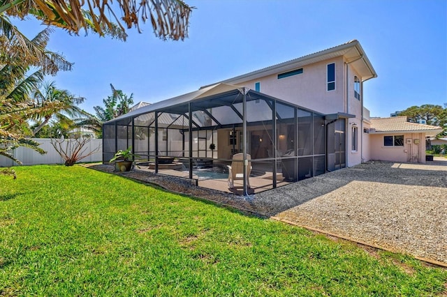 rear view of house with a yard, a patio, stucco siding, glass enclosure, and a fenced backyard