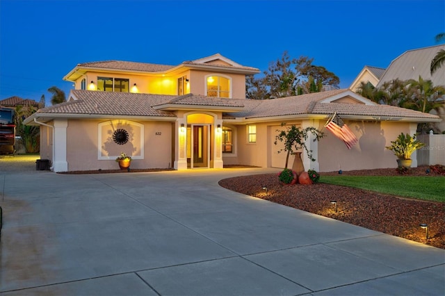 mediterranean / spanish home with concrete driveway, a tiled roof, an attached garage, and stucco siding