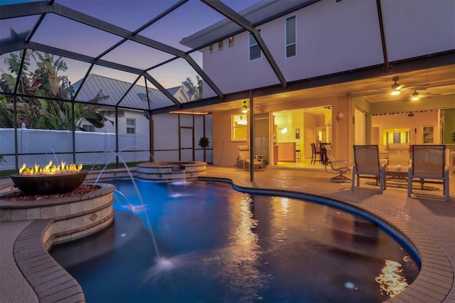 pool at dusk featuring a patio, glass enclosure, and a pool with connected hot tub