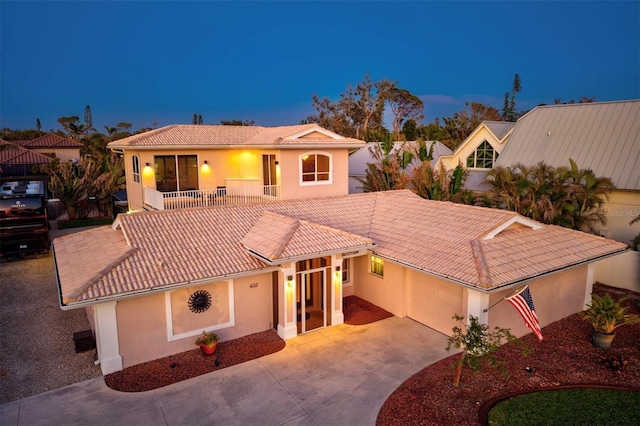 mediterranean / spanish-style house with concrete driveway, a tile roof, a balcony, and stucco siding