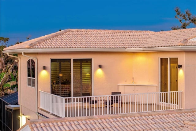 rear view of property with a tiled roof and stucco siding