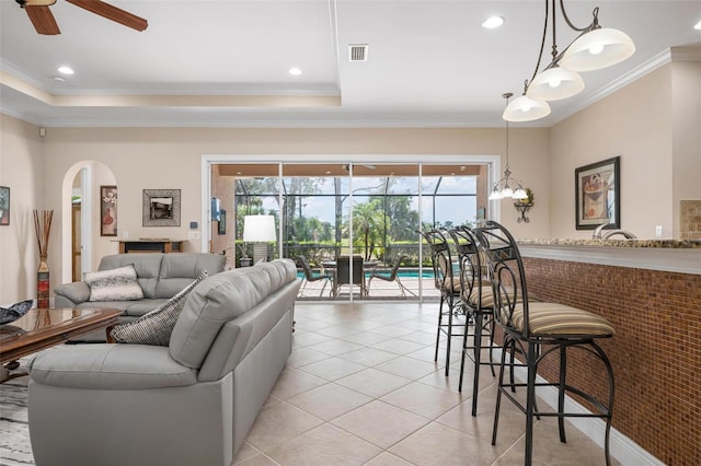 living room with a wealth of natural light, arched walkways, visible vents, and crown molding