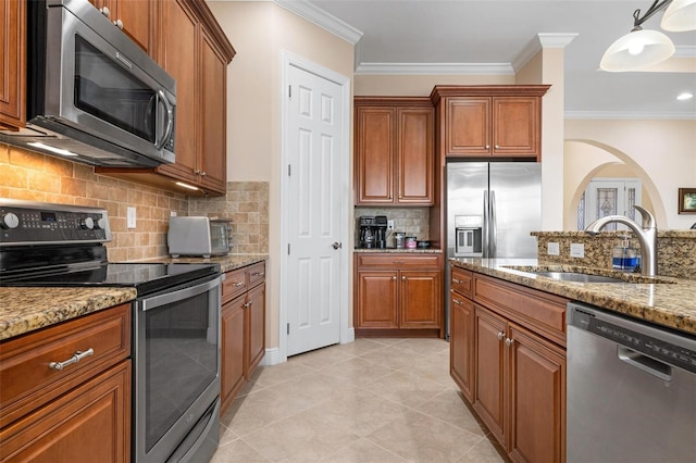 kitchen featuring crown molding, appliances with stainless steel finishes, a sink, and brown cabinets