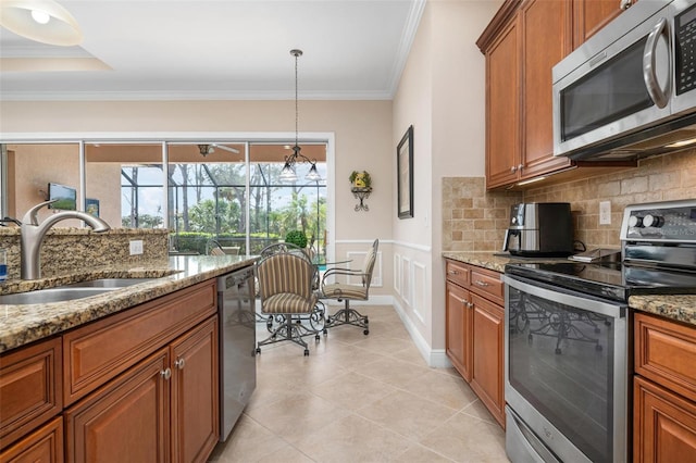 kitchen featuring appliances with stainless steel finishes, brown cabinetry, a sink, and tasteful backsplash