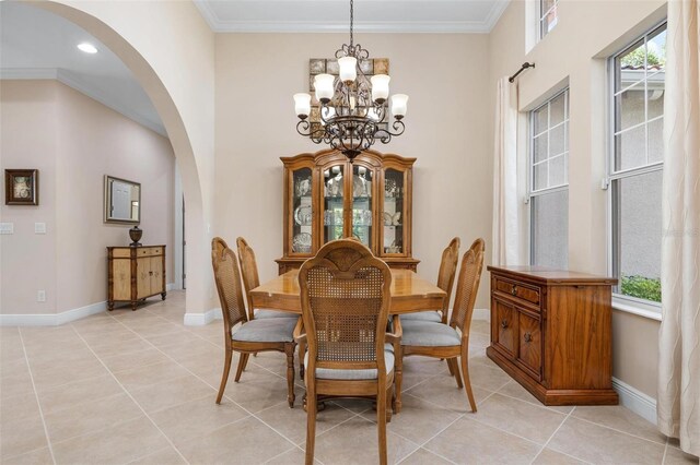 dining area with arched walkways, baseboards, light tile patterned flooring, and crown molding