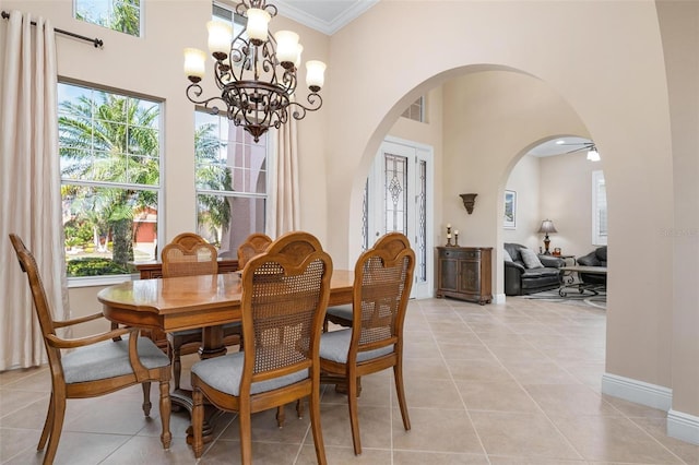 dining space with ornamental molding, arched walkways, a high ceiling, and light tile patterned floors