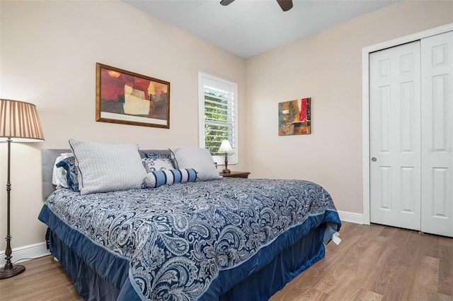 bedroom featuring a ceiling fan, a closet, baseboards, and wood finished floors