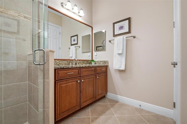 bathroom featuring tile patterned flooring, a shower stall, baseboards, and vanity