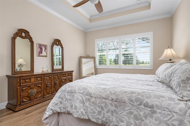 bedroom featuring a ceiling fan, crown molding, a tray ceiling, and wood finished floors