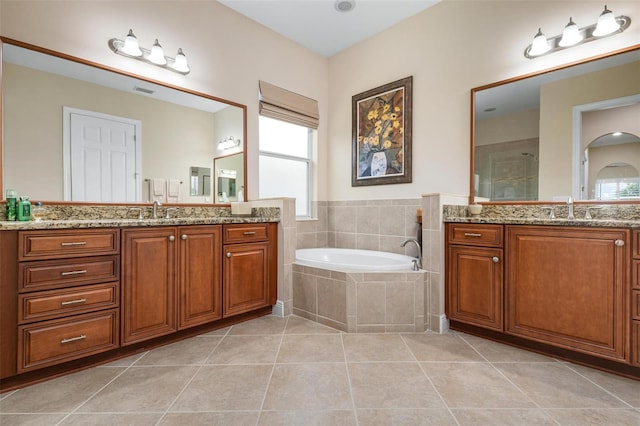 bathroom featuring a bath, tile patterned flooring, two vanities, and a sink