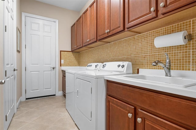 washroom with light tile patterned floors, a sink, tile walls, washer and dryer, and cabinet space