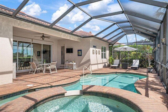 view of swimming pool with ceiling fan, a patio, glass enclosure, and a pool with connected hot tub