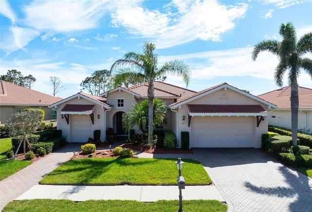 view of front of house featuring a garage, a tile roof, decorative driveway, stucco siding, and a front yard