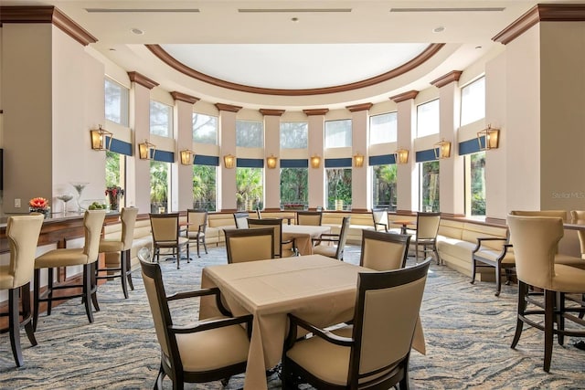 carpeted dining area featuring a tray ceiling, crown molding, and a high ceiling