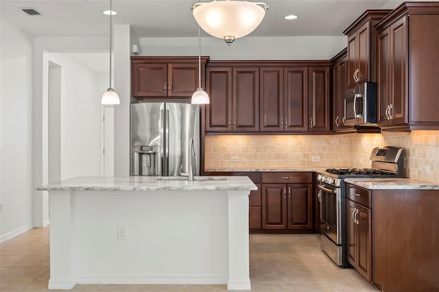 kitchen featuring light stone counters, visible vents, hanging light fixtures, appliances with stainless steel finishes, and a sink