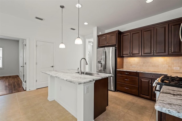 kitchen with decorative light fixtures, a center island with sink, visible vents, appliances with stainless steel finishes, and a sink