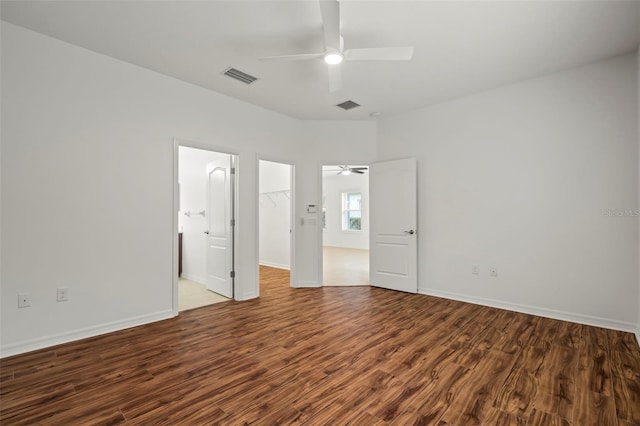 unfurnished bedroom featuring a closet, a spacious closet, visible vents, and wood finished floors