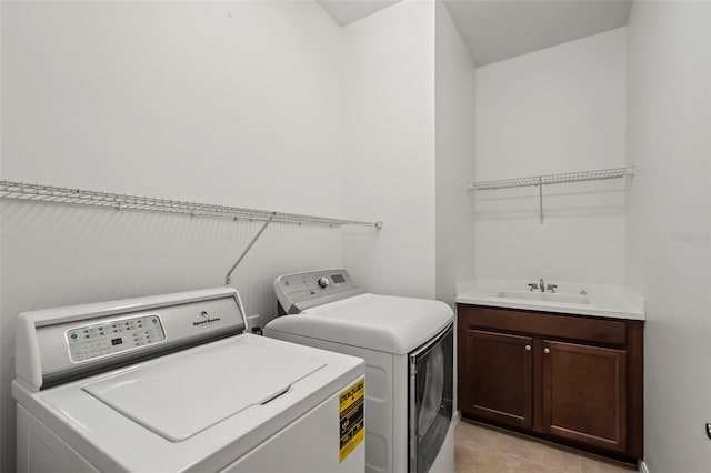 clothes washing area with cabinet space, washer and dryer, a sink, and light tile patterned flooring