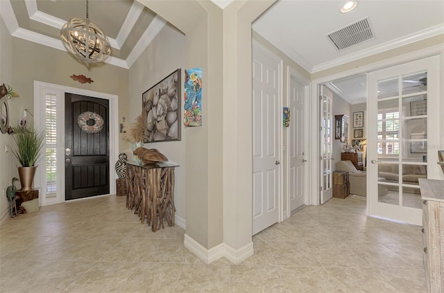 entrance foyer featuring light tile patterned floors, crown molding, visible vents, baseboards, and an inviting chandelier