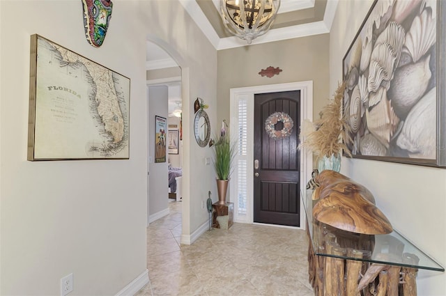 foyer entrance featuring baseboards, arched walkways, a chandelier, and crown molding