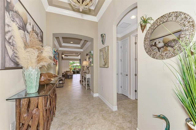 hall with arched walkways, visible vents, baseboards, a raised ceiling, and crown molding