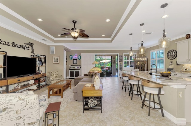 living room with arched walkways, a ceiling fan, a raised ceiling, and crown molding