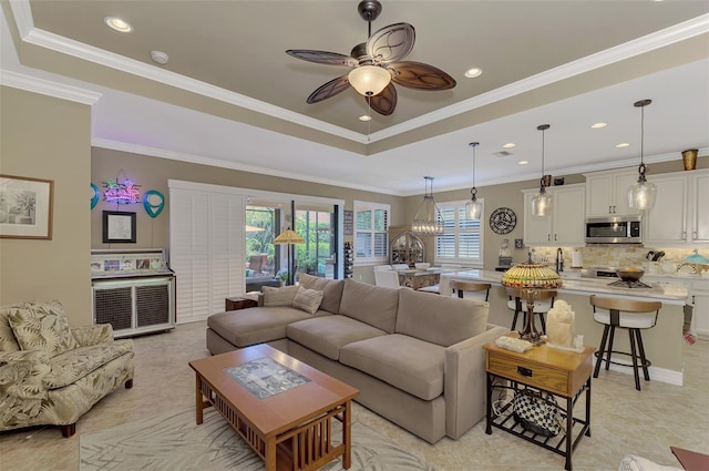 living area with recessed lighting, a raised ceiling, crown molding, and ceiling fan with notable chandelier