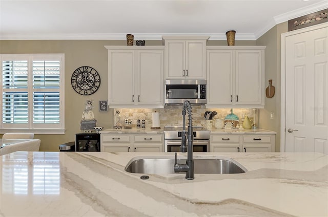 kitchen with stainless steel appliances, white cabinets, ornamental molding, and backsplash