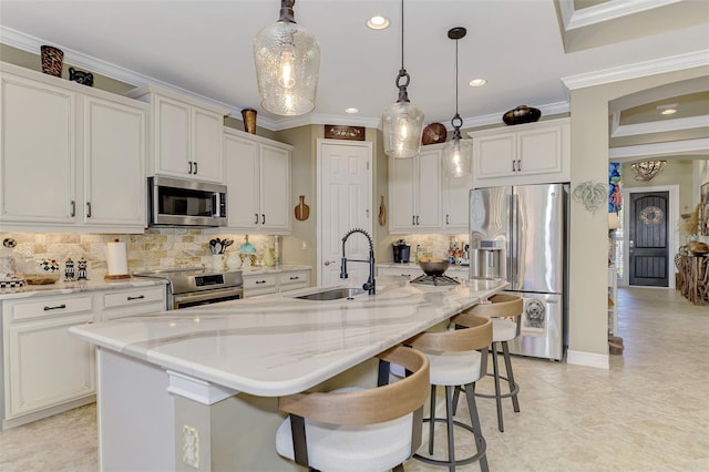 kitchen featuring stainless steel appliances, hanging light fixtures, ornamental molding, white cabinetry, and a sink