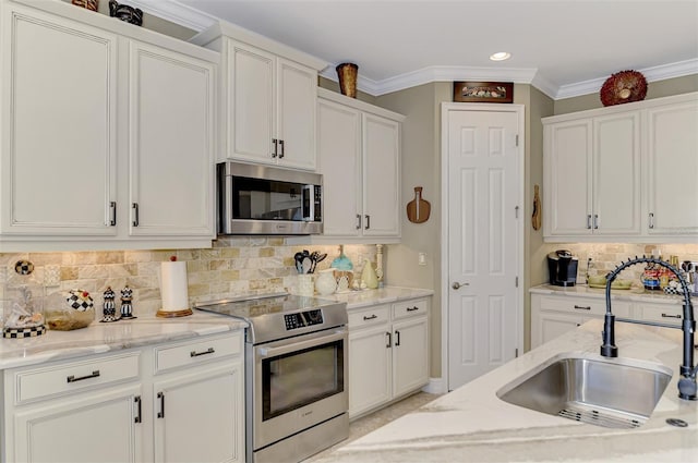 kitchen featuring crown molding, white cabinetry, stainless steel appliances, and a sink