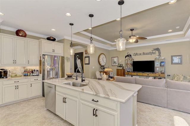 kitchen with appliances with stainless steel finishes, a raised ceiling, a sink, and open floor plan