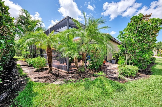 view of side of property featuring a lanai, a patio area, and a lawn