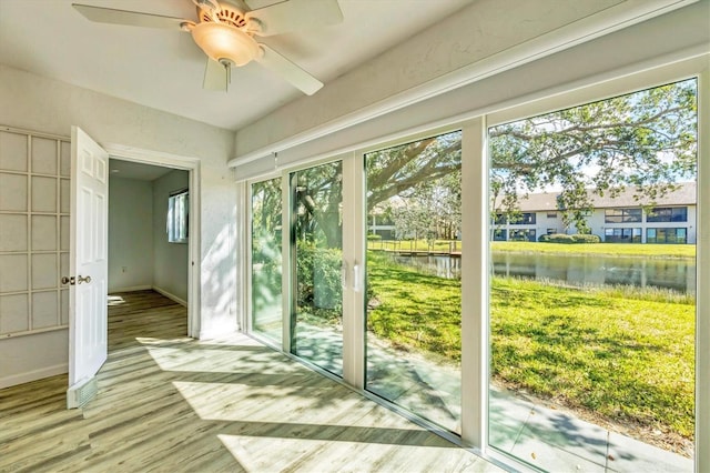 doorway with a water view, light wood finished floors, plenty of natural light, and ceiling fan