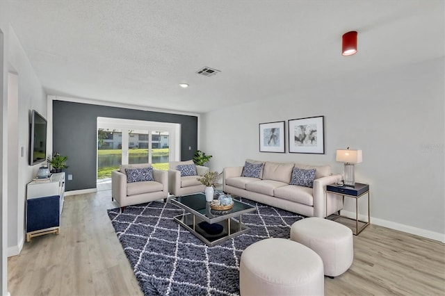 living room featuring wood finished floors, visible vents, and baseboards