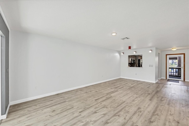 unfurnished living room with visible vents, light wood-style flooring, and baseboards