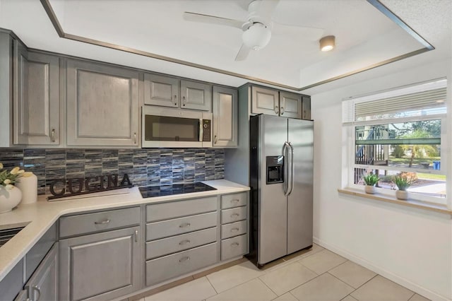 kitchen featuring appliances with stainless steel finishes, decorative backsplash, light countertops, and gray cabinetry